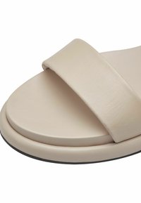 Beige schuifsandaal met een brede, gladde leren band en een ronde voetbed. Heeft een lichte verhoging op de zool en een zwarte buitenzool.