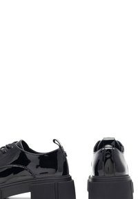 Czarne lakierowane platformy z grubymi żebrowanymi podeszwami, sznurowane z przodu i z pętlami na piętach, pokazane z bocznego i tylnego kąta.