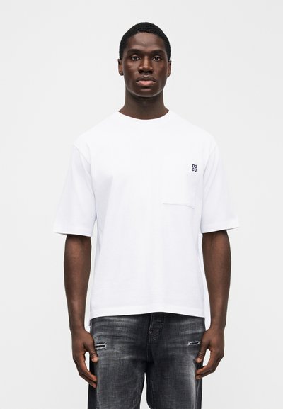 Λευκό βαμβακερό t-shirt με κοντά μανίκια και τσέπη στο αριστερό στήθος με μικρό μαύρο λογότυπο. Συνδυάζεται με σκουρόγκρι σκισμένα τζιν.