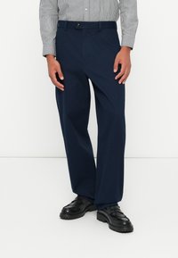 Granatowe, szerokie spodnie wykonane z gładkiego materiału. Posiadają zapięcie na guzik oraz szlufki na pasek, w zestawieniu z czarnymi butami wsuwanymi.