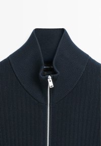 Marineblauer Baumwollpullover mit gerippter Textur, hohem Kragen und Frontreißverschluss, ausgestattet mit einem silbernen Reißverschluss und einem Stoffetikett.