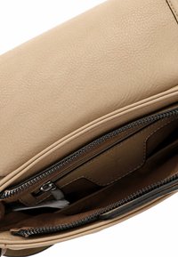 Interno della borsa a tracolla in pelle beige con una finitura liscia e texture. Presenta una cerniera scura e una tasca per l'organizzazione.