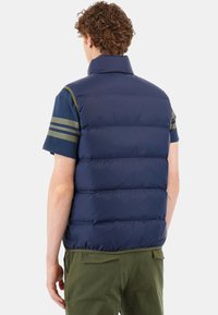 Mörkblå pufferväst med hög krage och horisontell sömnad, med olivgröna randiga detaljer på axlarna.