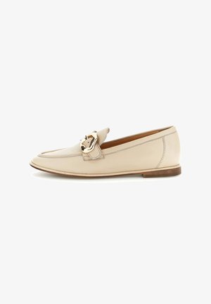 Beige leren loafer met een lage hak en gouden gespsluiting op het bovenwerk, afgebeeld tegen een witte achtergrond.