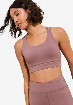 Lila sportos melltartó kerekített nyakkivágással, futóhátrész pántokkal és széles pánttal. Simogató, rugalmas anyagból készült.