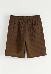 Shorts marron côtelés avec taille élastique et une poche à rabat unique sur le côté droit, présentés sur un fond clair.