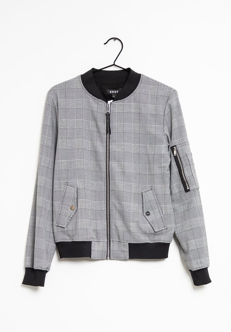 Veste bomber à carreaux gris avec col, poignets et ceinture noirs, fermeture éclair devant, deux poches à rabat à l'avant et une poche zippée sur la manche gauche.