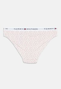 Puuvillane bikiinipüksik valge vöökohaga, millel on kiri "TOMMY HILFIGER". Hele roosakas taust, mis on kaetud väikeste lillemustritega.