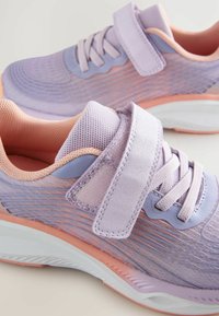 Des chaussures de sport violet clair dotées d'une tige en maille avec des détails texturés, des accents roses contrastants et une bande Velcro pour un maintien sécurisé.