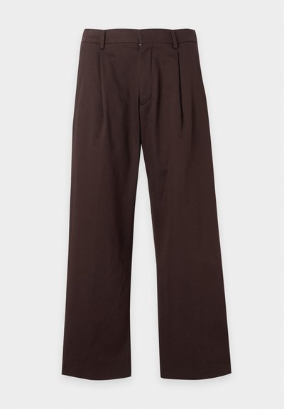 Pantalon marron foncé à jambes larges avec passants de ceinture, plis devant et fermeture éclair sur un fond clair uni.
