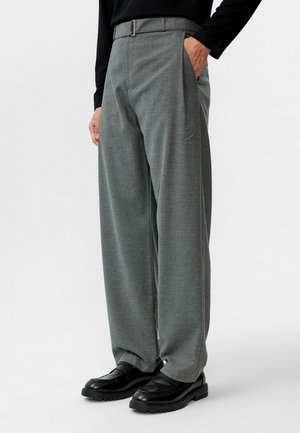 Grijze op maat gemaakte broek van gestructureerde stof met voorzakken en een riem. Gecombineerd met zwarte schoenen, met een rechte pasvorm.