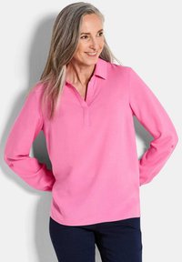 Blusa rosa a maniche lunghe con colletto a punte, realizzata in tessuto morbido. Caratterizzata da maniche con bottoni e una vestibilità rilassata.