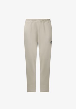 Pantalon de survêtement beige avec taille élastique, jambes fuselées et petit logo noir sur la cuisse droite, présenté sur un fond blanc.