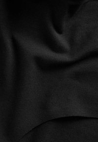 Tessuto nero con morbide pieghe e una sottile tessitura testurizzata, creando ombre e riflessi delicati sulla superficie.