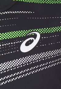 Musta urheilupaita, jossa on valkoisia ja vihreitä viistoja raitoja. Brändilogo valkoisena vasemmassa alkulmassa. Sileä pinta.