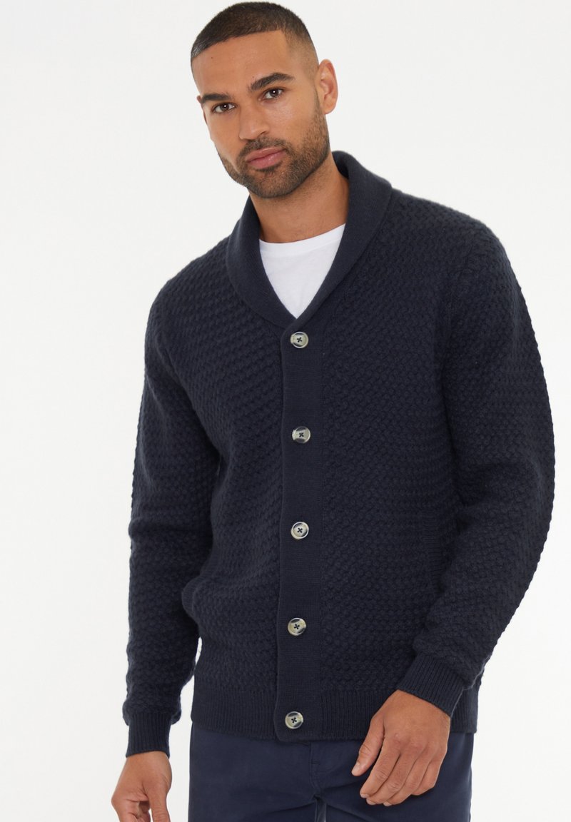 Cárdigan de punto en color navy con un patrón texturizado, cuello de chal y cierre de cinco botones con botones en contraste.