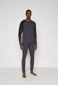 Athletic long-sleeve top and fitted pants in dark gray with black accents. Smooth fabric, raglan sleeves, and a slim fit design.