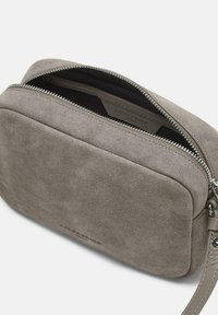 Graue Wildlederhandtasche in rechteckiger Form, ausgestattet mit einem silbernen Reißverschluss und einem abnehmbaren Tragegurt. Glatte Textur und minimale Branding-Details.