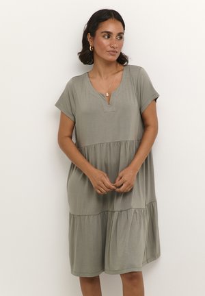 Olive green, short-sleeve dress with a V-neck, tiered design, relaxed fit, and soft fabric texture, hitting mid-calf length.