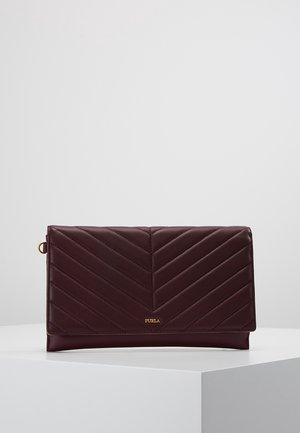 Ciemnobrązowa skórzana kopertówka z przeszyciem w kształcie jodełki i małym złotym logo Furla, prezentowana na białym pedestale na jasnym tle.