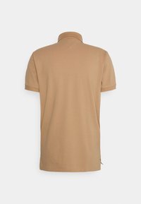 Polo shirt beige à manches courtes vu de dos, avec un col côtelé et un ourlet droit, sur fond uni.