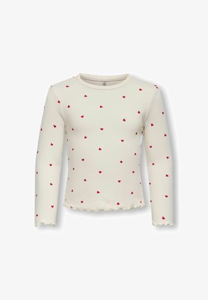 Witte lange mouw top van ribstof, met een patroon van kleine rode harten en een golvende zoom aan de onderkant en mouwen.