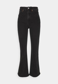 Svarta denimbyxor med vid ben och hög midja, med knappstängning, framfickor och en slät yta. Nederkanten är något klippt.