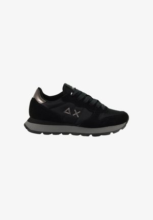 Sneaker nera con lacci, suola grigia, dettaglio metallico sul tallone e simboli a triangolo e X ricamati sul pannello laterale.
