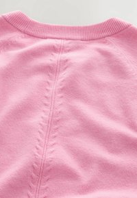 Pull rose clair avec un col côtelé et une couture texturée au centre, ornée d'un motif de points décoratifs de chaque côté.