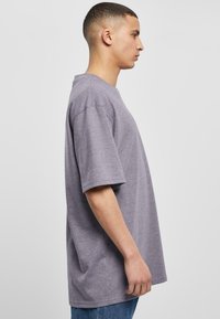 Gray cotton t-shirt with a relaxed fit, drop shoulder design, short sleeves, and a crew neckline, paired with blue jeans.