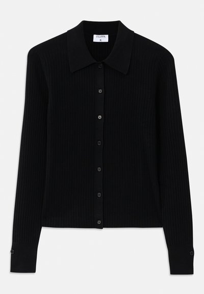 Črn rebrast kardigan z dolgimi rokavi, koničastim ovratnikom in sprednjim zapiranjem na gumbe, ki vključujejo majhne okrogle gumbe. Teksturirani material dodaja globino.