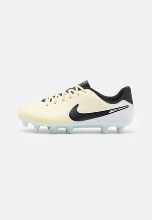 Botas de fútbol Nike en color crema y negro, con una parte superior sintética texturizada, diseño con cordones y suela con tacos translúcida.
