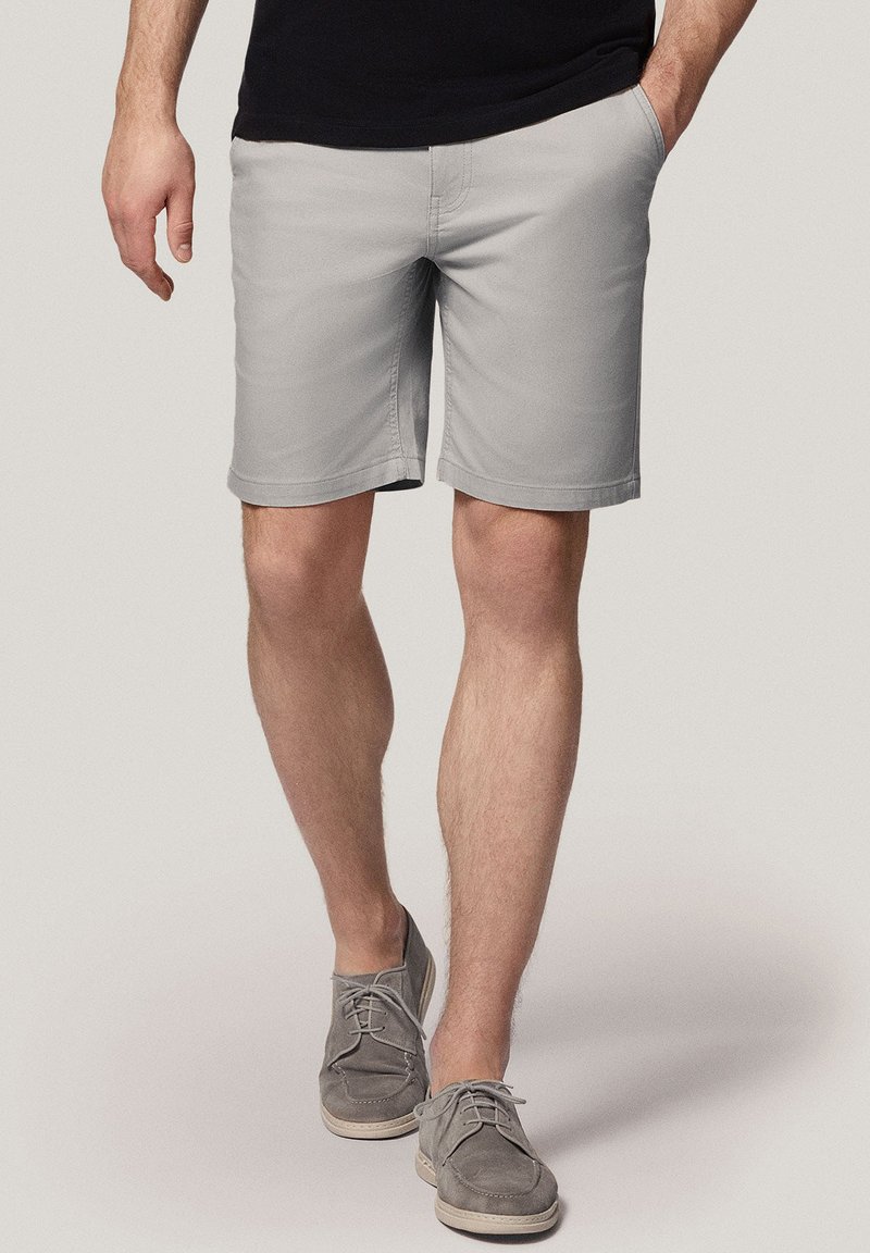 Szare spodenki o gładkiej strukturze, z bocznymi kieszeniami i prostym krojem, w połączeniu z szarymi zamszowymi butami.