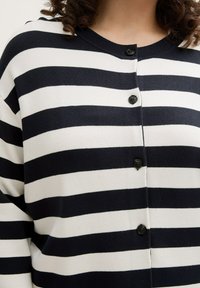 Gestreifter Cardigan in Marineblau und Weiß, mit Rundhalsausschnitt, Knopfverschluss vorne und schwarzen Knöpfen. Weiches Strickmaterial mit horizontalen Streifen.