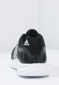 Černá sportovní bota s síťovaným svrškem, bílými akcenty a designem se třemi pruhy. Disponuje polstrovanou podešví a zaobleným tvarem zadní části.