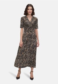 Maxi šaty v leopardím potisku s výstřihem do V, krátkými rukávy a uzlem v pase. Paleta barev zahrnuje hnědou, černou a béžovou.