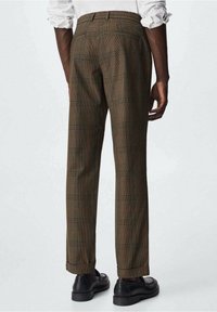 Brązowe spodnie w kratę o dopasowanym kroju, z delikatnym wzorem w kratę w odcieniach pomarańczowego i zielonego, wykończone mankietami.