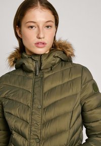 Olijfgroene pufferjack met een afneembare bontgevoerde capuchon, horizontaal quiltpatroon en knoopsluiting. Voorzien van een zijlogo-embleem.