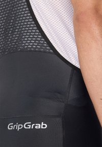 Nærbilde av en person som har på seg svarte sykkelshorts med hvit mesh øvre del og GripGrab-logo på korsryggen.