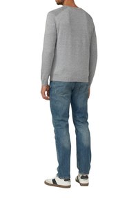 Grau gestrickter Pullover mit gerippten Bündchen und Saum, getragen mit blauen Jeans und weißen Sneakers mit einem schwarzen Streifen.