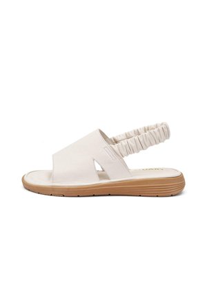 Biała sandałka z odkrytymi palcami, szerokim paskiem ze skóry, elastycznym marszczonym paskiem z tyłu oraz jasnobrązową teksturowaną podeszwą, pokazana z boku na białym tle.