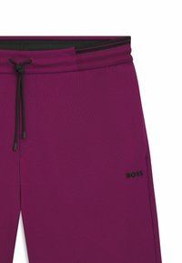 Purple sweatpants with black drawstring and waistband. Features a side pocket and a black "BOSS" logo on the thigh. Smooth texture.