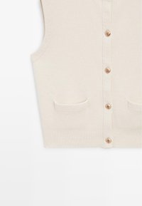 Gilet lavorato a maglia senza maniche color crema con bottoni frontali e due piccole tasche anteriori, caratterizzato da orlo e bordi delle maniche a costine.