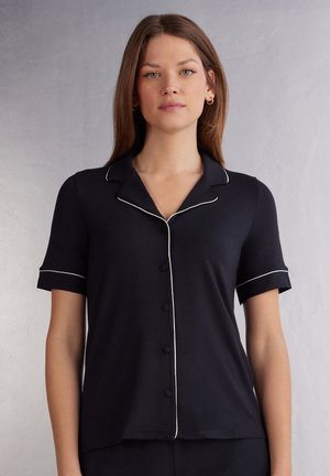 Navy pyjama top met korte mouwen, witte bies op de kraag en manchetten, vijf-knoopsluiting aan de voorkant, zachte stof, ontspannen pasvorm, gladde textuur.