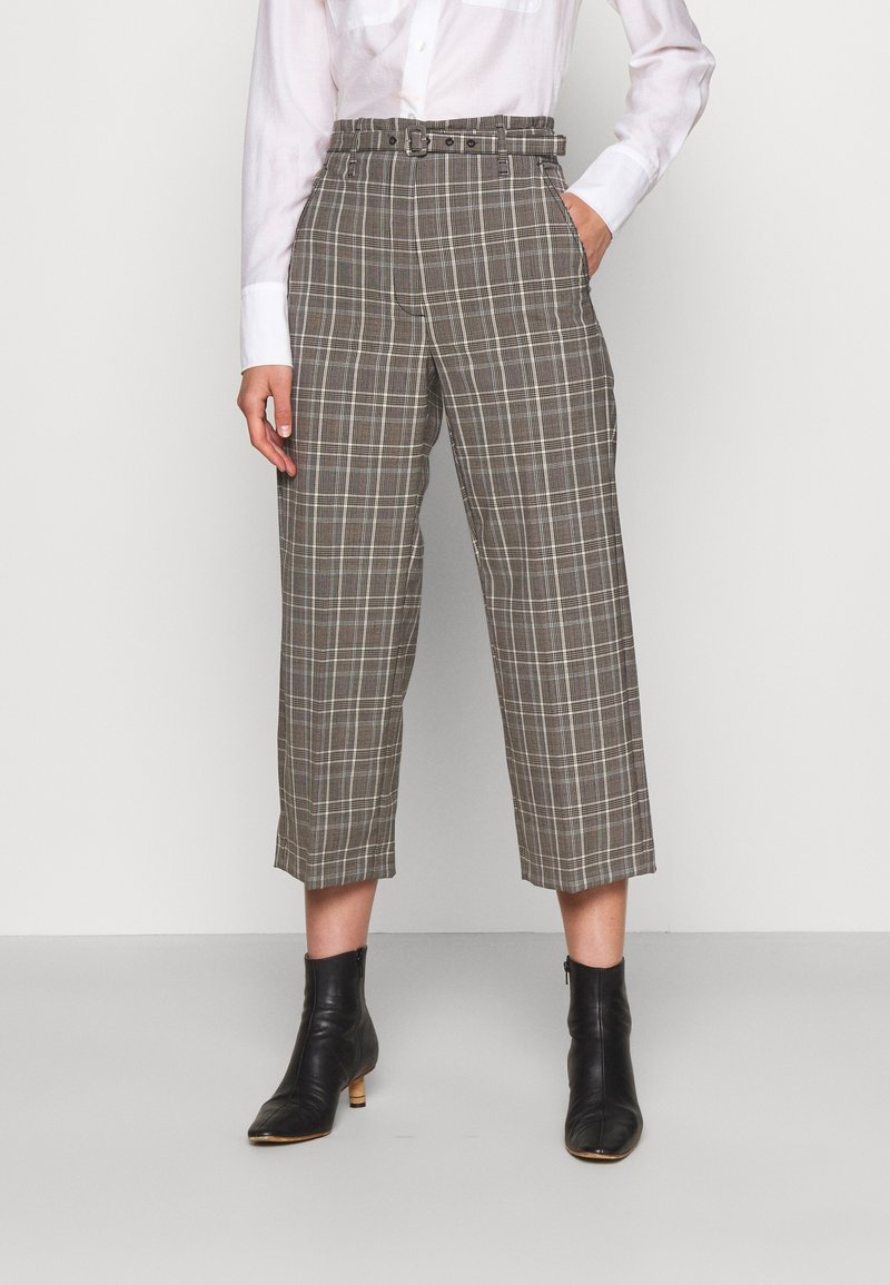 Bruna och grå rutiga byxor med hög midja som har bälte, vida avklippta ben och sidofickor, kombinerat med svarta ankelstövlar.