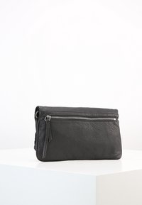 Pochette in pelle nera con superficie testurizzata, dotata di chiusura a zip argentata e nappina laterale per un dettaglio in più.