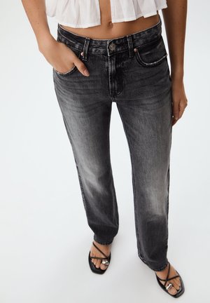 High-waisted black jeans featuring a faded wash, straight-leg cut, five-pocket design, and silver hardware accents.