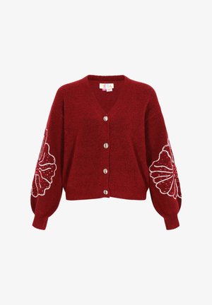 Czerwony sweter robiony na drutach z dekoltem w serek, pięcioma srebrnymi guzikami oraz oversize'owymi rękawami z białymi haftami kwiatowymi i ozdobami.