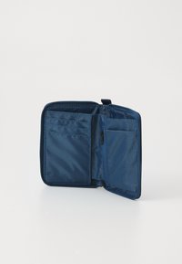 Portefeuille compact en tissu bleu ouvert, montrant plusieurs emplacements pour cartes et une poche à pièces zippée sur un fond blanc uni.
