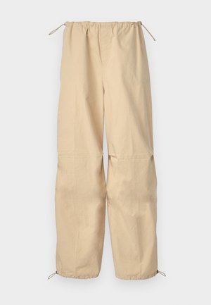 Pantalons beige légers avec une taille à cordon et des ourlets ajustables. Texture lisse, coupe ample, sans motifs ni éléments visibles.
